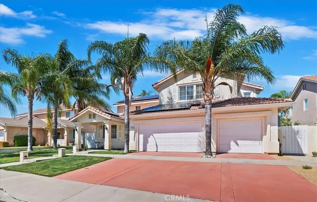 a front view of a house with a yard and palm trees