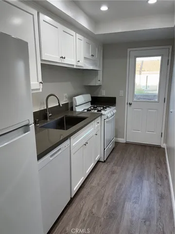 a kitchen with stainless steel appliances granite countertop a sink and cabinets with wooden floors
