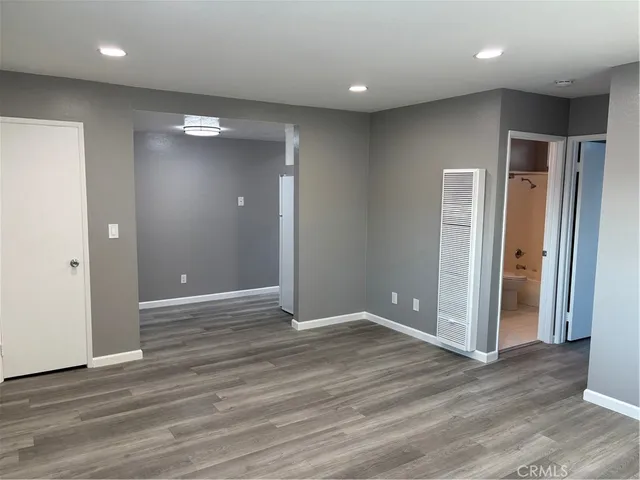 an empty room with wooden floor & bathroom space