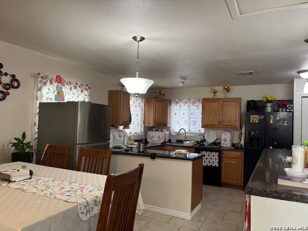 a kitchen with stainless steel appliances kitchen island granite countertop a sink a stove a refrigerator and a chandelier