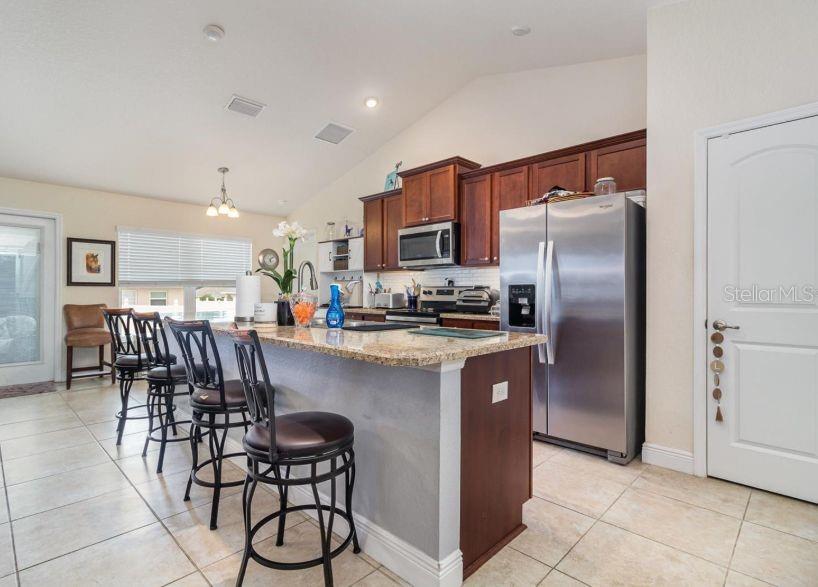 186 Northwest 44th Street Ocala, FL 34475 - Photo 11 of 36 a kitchen with stainless steel appliances granite countertop a refrigerator a stove a sink a dining table and chairs
