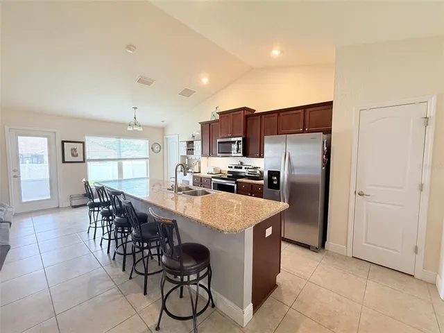 a large kitchen with kitchen island a large counter top space appliances and cabinets