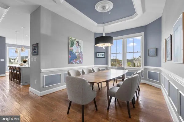 a kitchen with stainless steel appliances kitchen island granite countertop a stove a sink a refrigerator and white cabinets with wooden floor