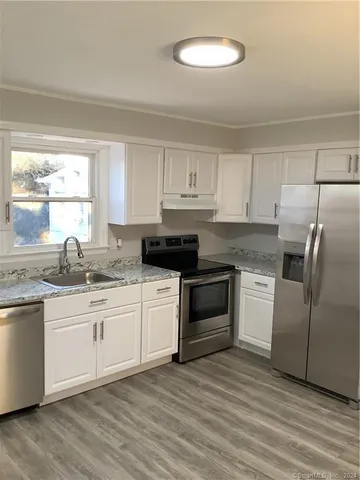 a kitchen with granite countertop a sink cabinets stainless steel appliances and a window