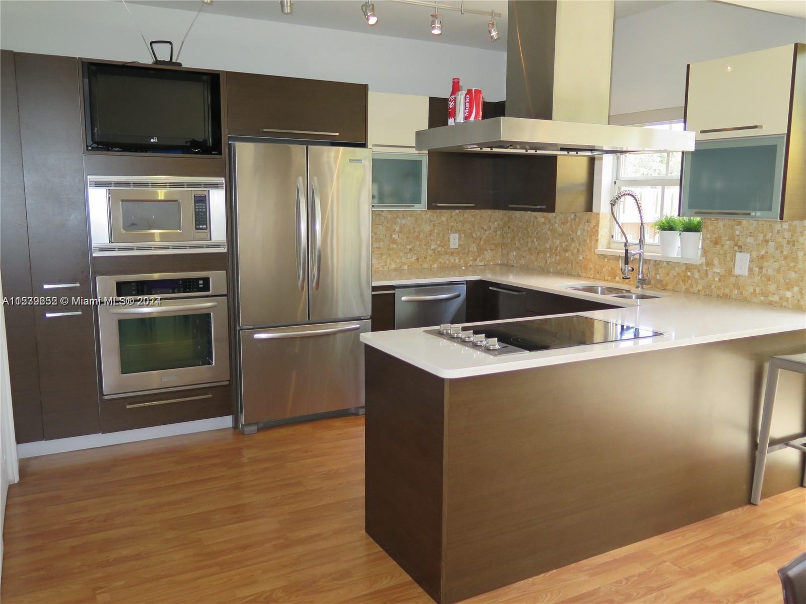 a kitchen with kitchen island a counter top space appliances and a sink