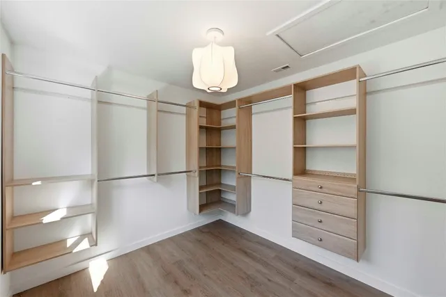 a walk in closet with wooden floor