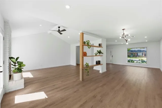 a view of an empty room and wooden floor and a ceiling fan