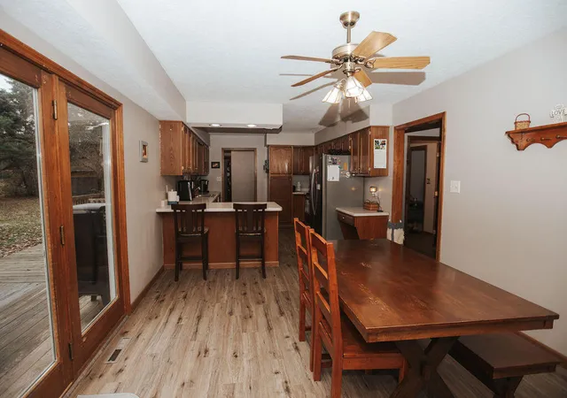 a kitchen with stainless steel appliances a dining table chairs refrigerator and cabinets