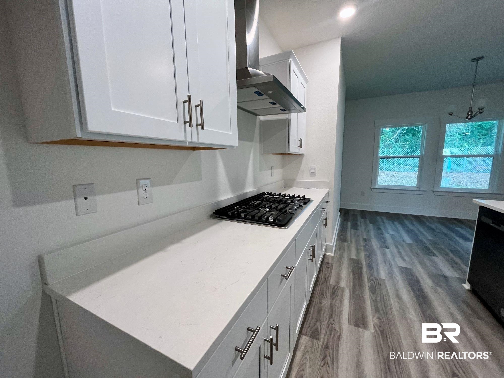 334 Barndling Street Fairhope, AL 36532 - Photo 15 of 34 Kitchen with white cabinetry, wall chimney range hood, gas stovetop, and wood-type flooring