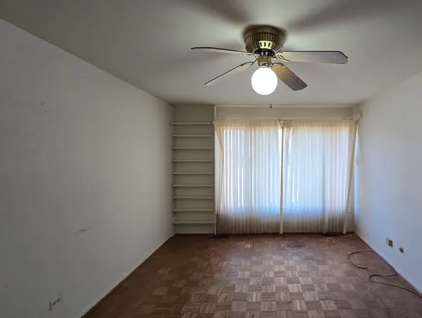 an empty room with a ceiling fan and window