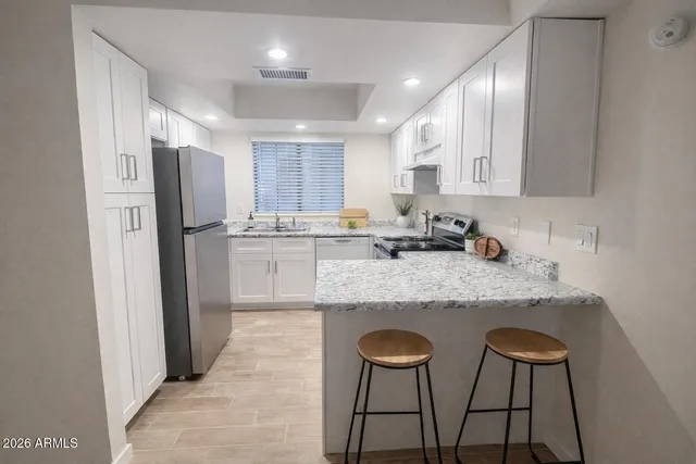 a kitchen with stainless steel appliances granite countertop a stove a sink and a refrigerator