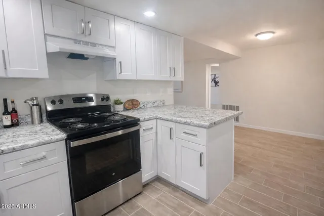 a kitchen with stainless steel appliances granite countertop a stove a sink and white cabinets