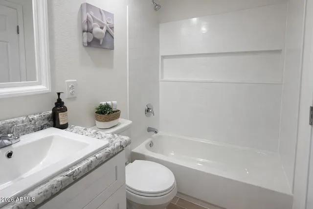 a bathroom with a granite countertop sink a toilet and bathtub