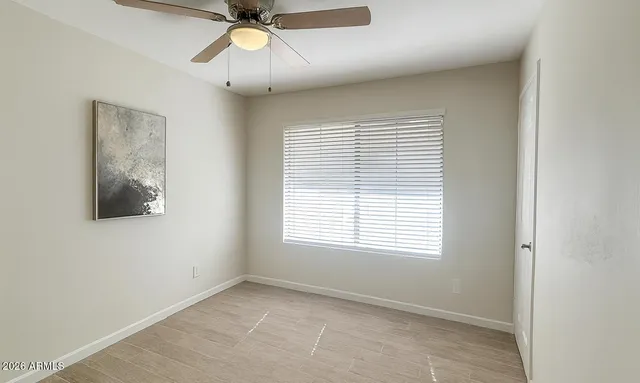 a view of an empty room with a window and a ceiling fan