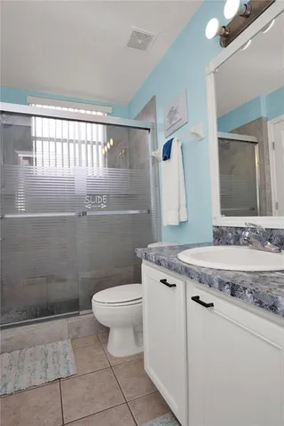 a bathroom with a granite countertop sink a toilet a mirror and shower