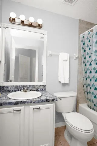 a bathroom with a granite countertop sink a toilet and a mirror