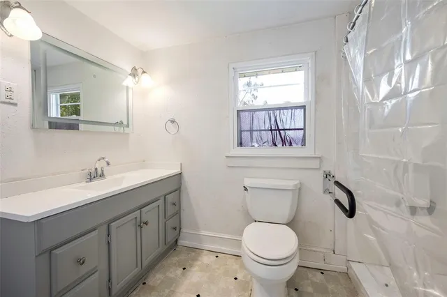 a bathroom with a toilet sink a mirror a vanity and window