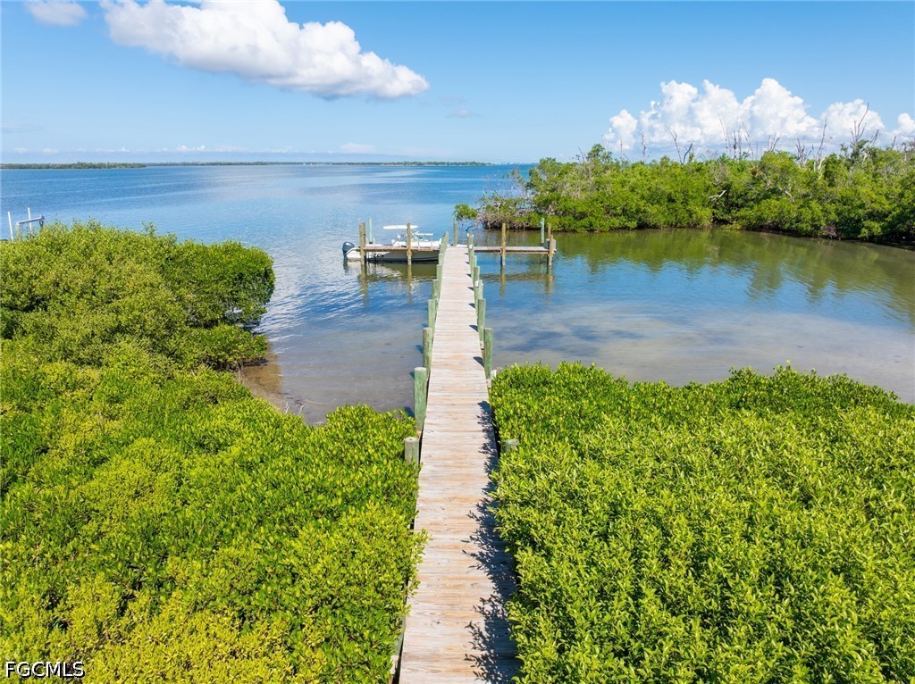 303 Useppa Useppa Island, Unit A Bokeelia, FL 33922 - Photo 13 of 50 a view of a lake with lawn chairs and large trees