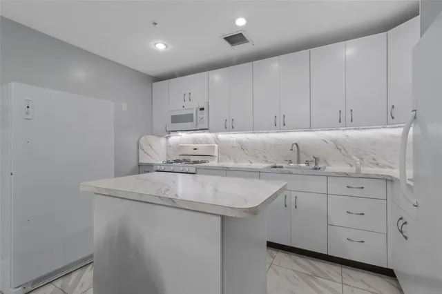 a kitchen with kitchen island granite countertop white cabinets and white appliances