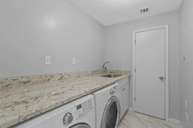 a utility room with granite countertop cabinets washer and dryer