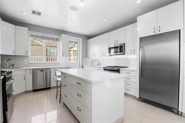 a kitchen with cabinets stainless steel appliances a sink and a window