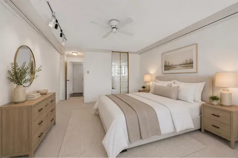 a spacious bedroom with a bed a dresser and potted plants on the dresser