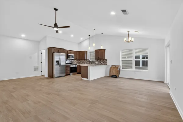 a view of a kitchen with stainless steel appliances kitchen island a large counter top and sink