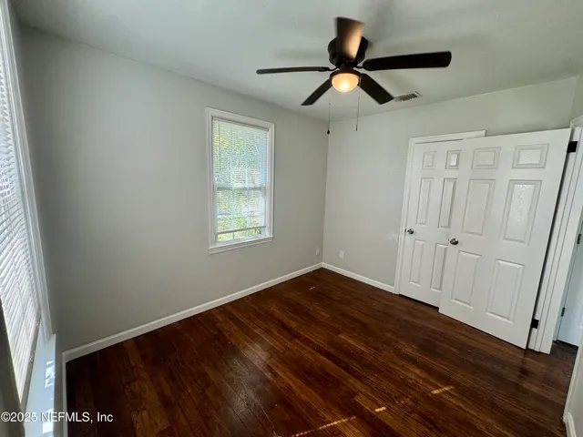 a view of empty room with wooden floor and fan