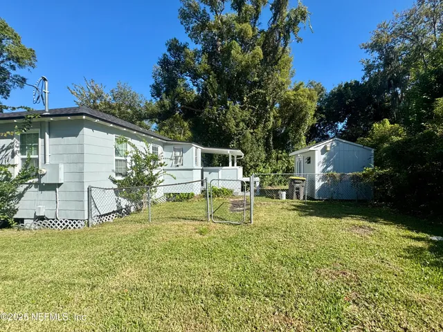 a view of a backyard with table and chairs potted plants and large tree