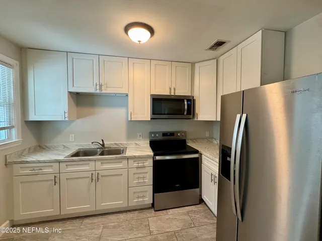 a kitchen with a refrigerator sink and cabinets