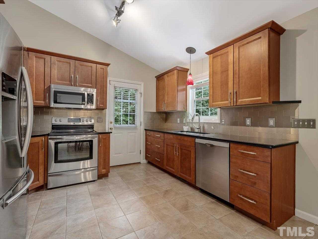 6441 Guess Road Durham, NC 27712 - Photo 10 of 30 a kitchen with stainless steel appliances granite countertop a stove a sink and a microwave