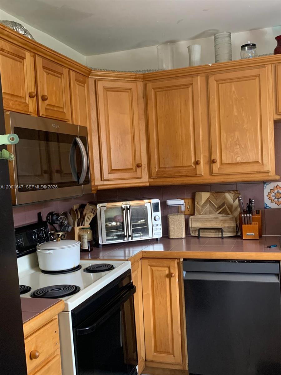 7010 Southwest 103rd Place Miami, FL 33173 - Photo 6 of 10 a kitchen with stainless steel appliances granite countertop a sink stove and cabinets