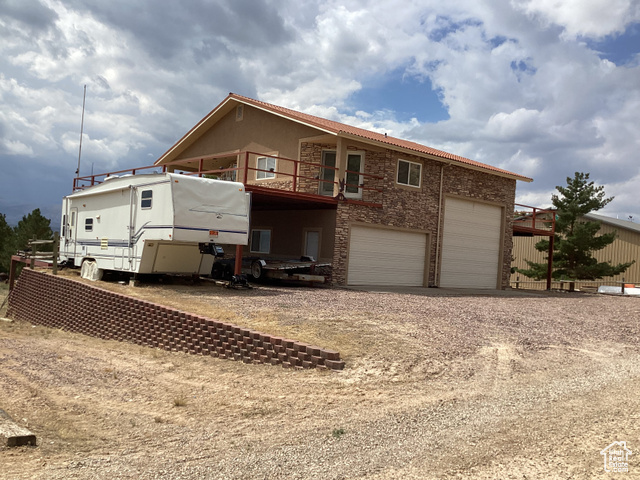3 Red Circle, Unit 19 Manila, UT 84046 - Photo 4 of 29 Rear view of house with driveway, stone siding, a deck, a garage, and a balcony