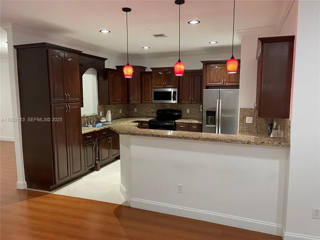 a kitchen with stainless steel appliances granite countertop a refrigerator a stove and a wooden floors