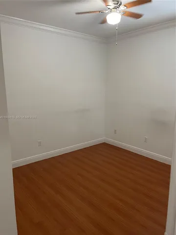 an empty room with wooden floor and fan