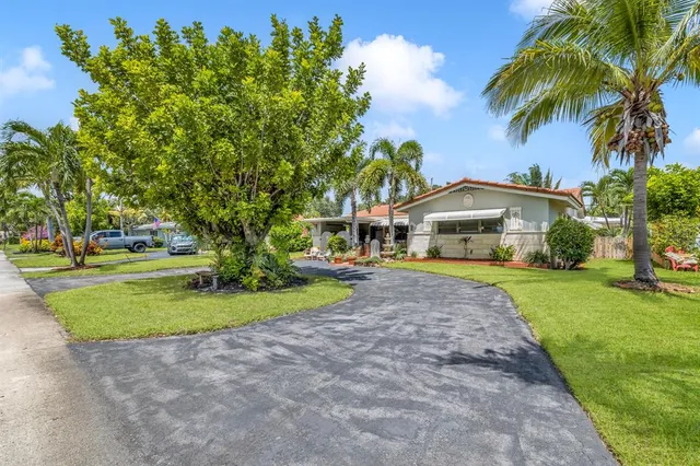 a front view of a house with garden and trees