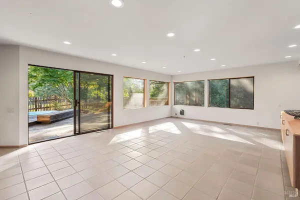 a view of an empty room with a window and kitchen view