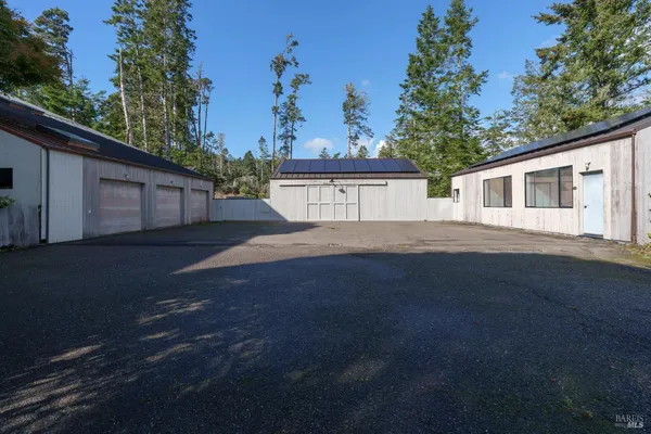a view of a wooden house with a yard and large trees