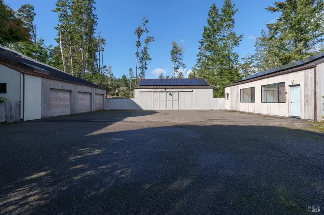 a view of a wooden house with a yard and large trees