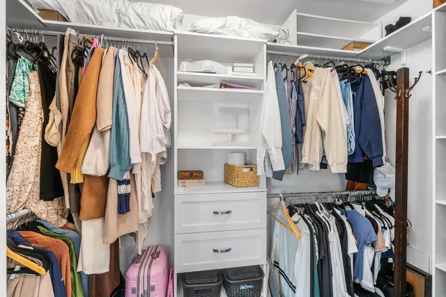 a view of walk in closet with clothes and shoes