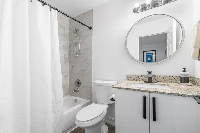 a bathroom with a granite countertop sink toilet a large mirror a shower and vanity