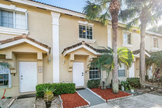 a view of a white house with a fountain and a large window with potted plants