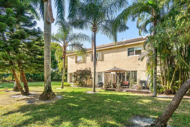 a view of a house with a big yard and palm trees