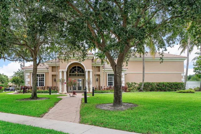 a front view of a house with a garden and trees