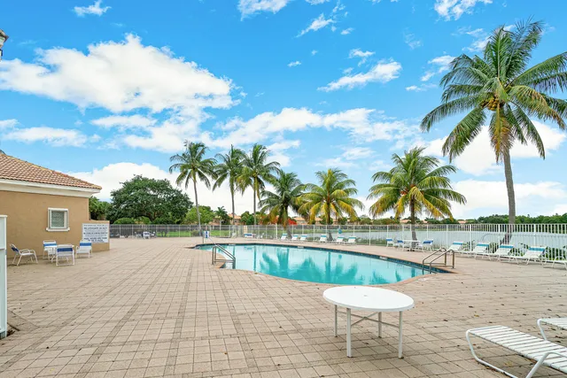 a view of a swimming pool with a lounge chair and palm trees