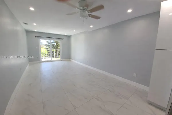 an empty room with windows and ceiling fan