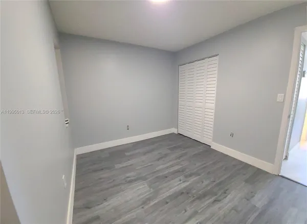 an empty room with wooden floor and white walls