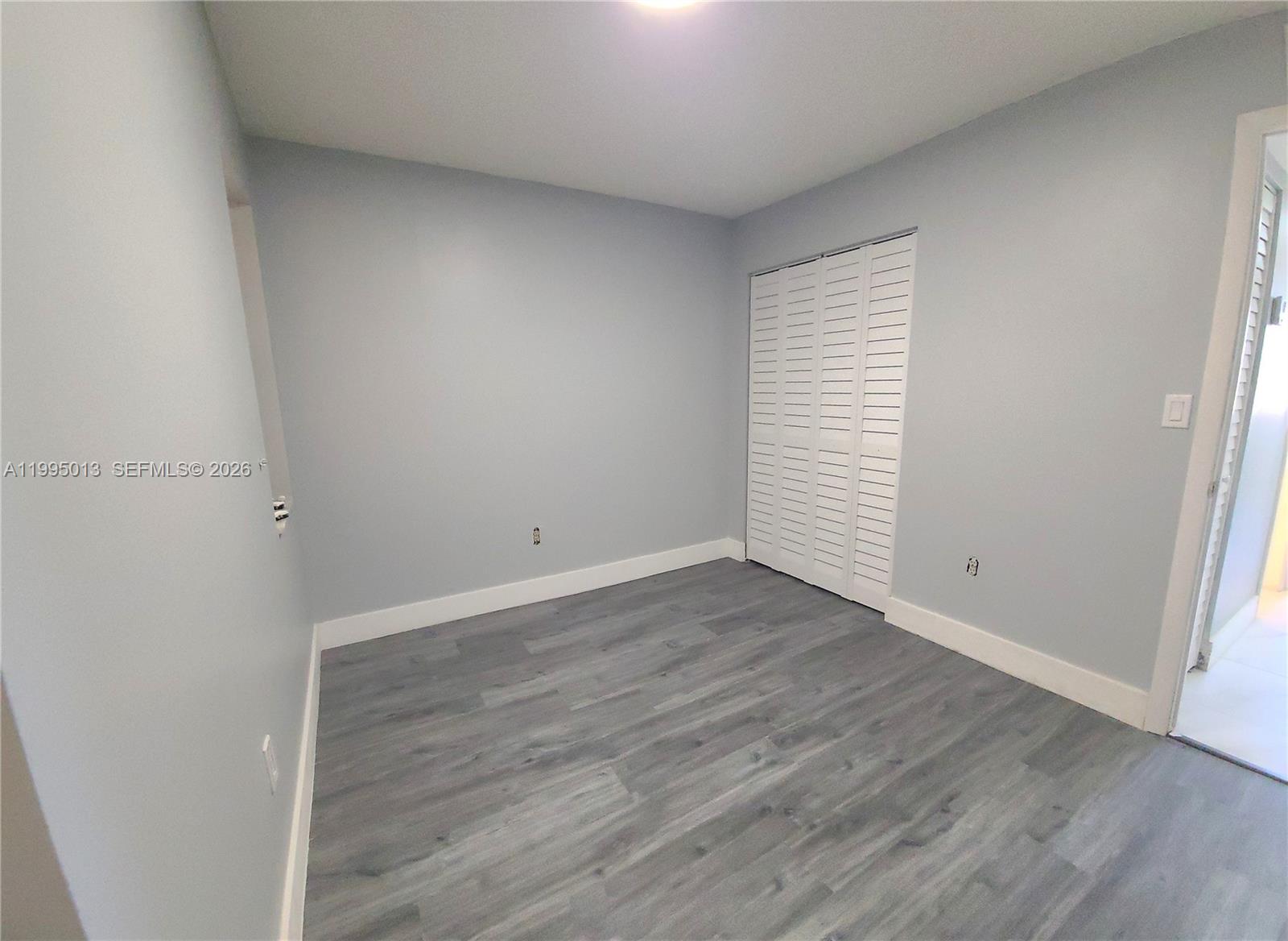 453 Southwest 2nd Street, Unit 306C Miami, FL 33130 - Photo 6 of 18 an empty room with wooden floor and white walls