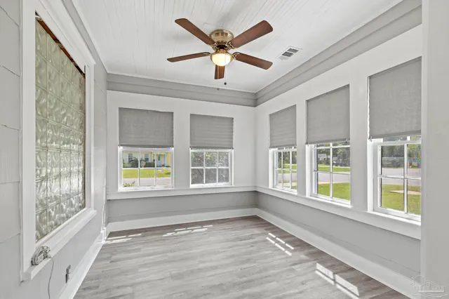 a view of an empty room with a window and wooden floor