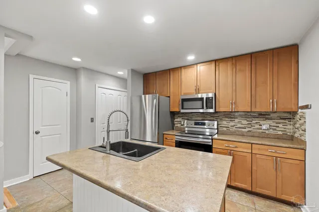 a kitchen with kitchen island a stove a sink and a refrigerator
